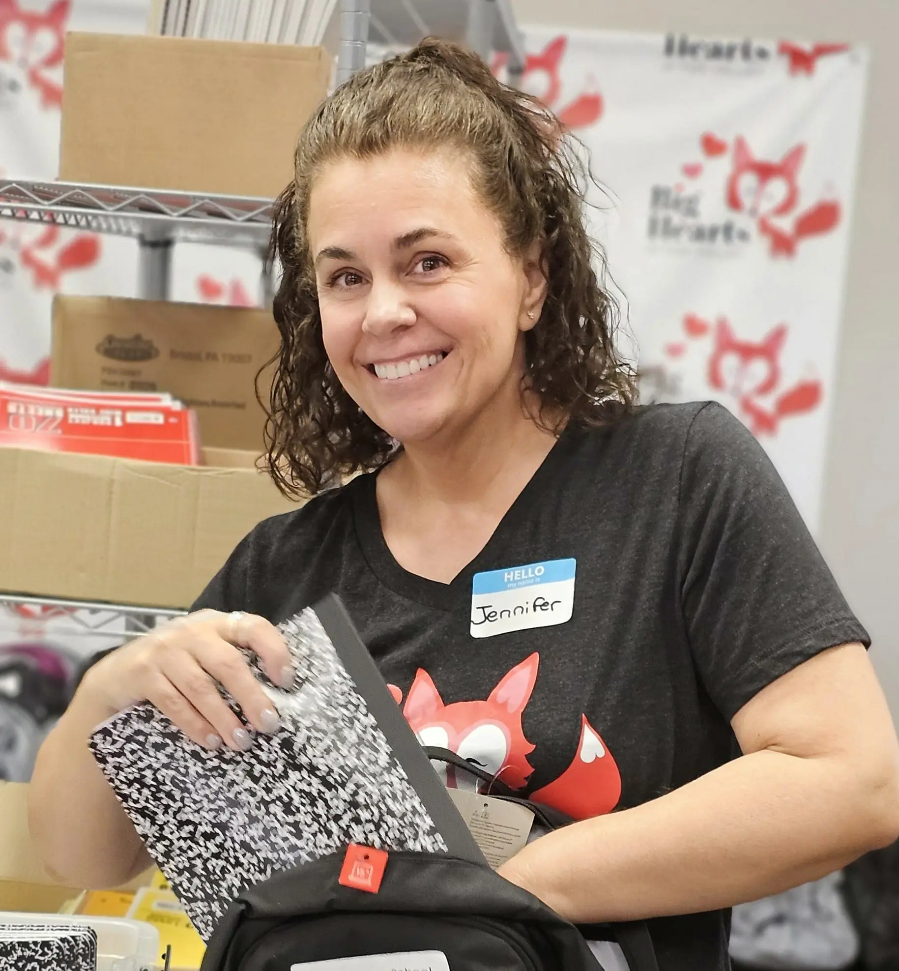 Smiling woman packing a backpack with notebooks.