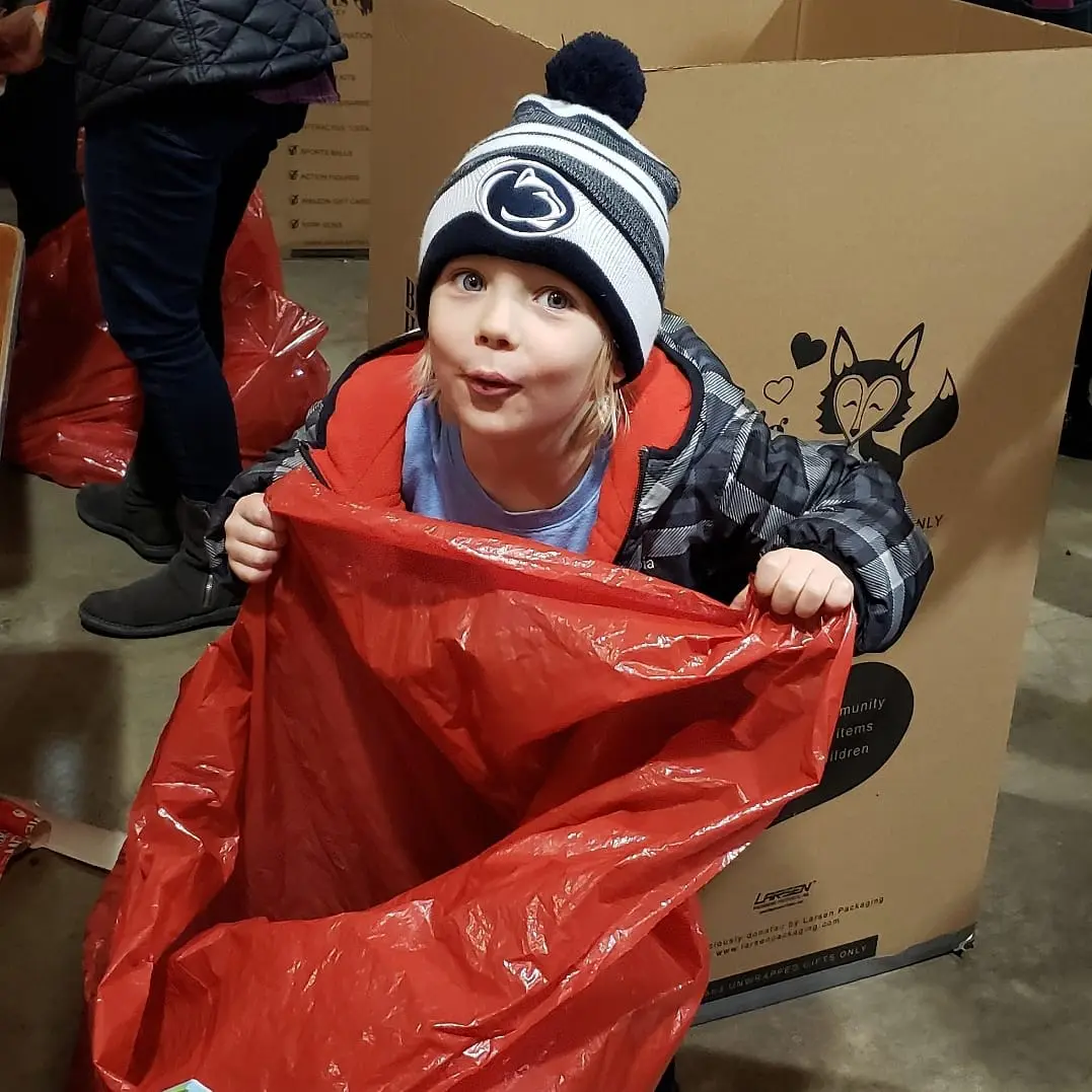 Child inside red bag, wearing winter clothes.