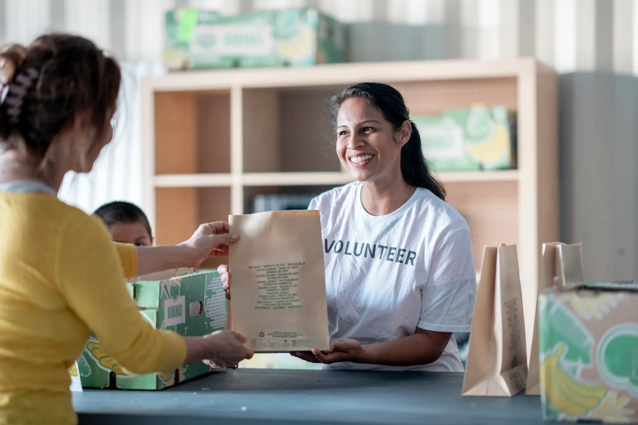 Volunteer handing out a paper bag, smiling.